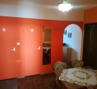Prenájom 2 izbový byt Poprad - loggia - Jedáleň v 2-izbovom byte s oranžovou stenou, podlahou s dreveným dekorom a oblúkom.