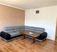 Na predaj zrekonštruovaný a kompletne zariadený 3 - izbový byt  v Hume - Šedá rohová pohovka s konferenčným stolíkom na podlahe s dreveným dekorom v 3-izbovom byte.