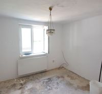 Pokojné bývanie v obci Kava + investícia do budúcnosti - Izba s lustrom a prázdnou podlahou na renováciu v rodinnom dome.