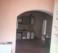 Pokojné bývanie v obci Kava + investícia do budúcnosti - Interiér rodinného domu s podlahou s dreveným dekorom a oblúkovým prechodom do kuchyne.