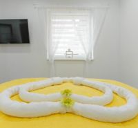 Moderný apartmán v centre Rajeckých Teplíc rovno oproti kúpeľom Afrodi - Spálňa Rekreačného apartmánu s oknom, televízorom a uterákmi naaranžovanými na posteli.