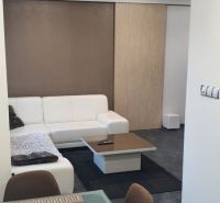 Nadštandardný, dômyselne zariadený 3-izbový byt  - PREDAJ. - Obývacia izba 3-izbového bytu s bielou sedačkou a stolom na prestieranie.