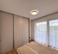 Prenájom nový 2-izbový byt -49m² Žilina-Vlčince, EUROTERRACE - Spálňa v 2-izbovom byte s posteľou, posuvnými dverami a závesmi na okne.