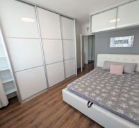 Moderný 2-izbový byt s balkónom a výhľadom - Spálňa v 2-izbovom byte s podlahou s dreveným dekorom, skriňou a posteľou.