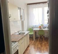 Predaj 3-izbový byt s loggiou a šatníkom – Kyjevská ul., Michalovce - Kuchyňa v 3-izbovom byte s bielymi skrinkami a podlahou s dreveným dekorom.
