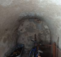 Na predaj chalupa  Banská Hodruša v tichej lokalite - Na obrázku je klenbová miestnosť s bicyklom, starým vybavením, pripomínajúca pivničný priestor.