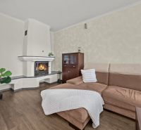 KARLOVA VES- Vila s investičným potenciálom a tromi samostatnými bytmi - Obývacia izba s krbom, hnedou sedačkou a podlahou s dreveným dekorom v rodinnom dome.