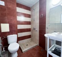 Moderná garsónka (41 m²) s výhľadom na bazén – Rezort ANTARES - Kúpeľňa s bezbariérovým sprchovým kútom, hnedými a béžovými obkladačkami v garsónke.