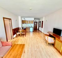3-izbový apartmán v prvej línii pri mori s Aktom 16 - Obývacia izba v 3-izbovom byte s podlahou s dreveným dekorom a jednoduchým zariadením.