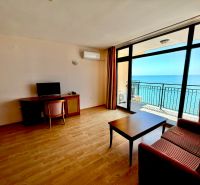 3-izbový apartmán v prvej línii pri mori s Aktom 16 - Obývacia izba v 3-izbovom byte s výhľadom na more a podlahou s dreveným dekorom.
