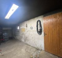 NA PREDAJ 6-IZB. RODINNÝ DOM, Senica – Čáčov - Garáž rodinného domu s drevenými dverami, regálmi a osvetlením, v obci Senica.