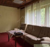 Chata na rekonštrukciu v lokalite Ružín - Bradan - Obývacia izba chaty s červeným kobercom a pohovkou, Košická Belá.