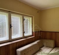 Chata na rekonštrukciu v lokalite Ružín - Bradan - Chata s rohovou sedačkou, dreveným obkladom a veľkými oknami.