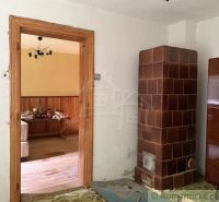 Chata na rekonštrukciu v lokalite Ružín - Bradan - Chata s kachľovou pecou, dreveným stolom a podlahou s dreveným dekorom.