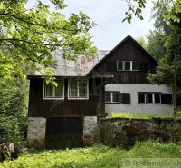 Chata na rekonštrukciu v lokalite Ružín - Bradan - Chata v Košickej Belej obklopená zeleňou a kamenným múrom.