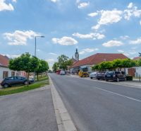 Častá RD s čiastočnou rekonštrukciou a veľkým pozemkom 2934m2 - Ulica Hlavná v Častej s rodinnými domami a zaparkovanými autami.