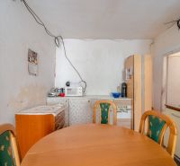 Častá RD s čiastočnou rekonštrukciou a veľkým pozemkom 2934m2 - Jedáleň v rodinnom dome s dreveným stolom a kuchynskými spotrebičmi.