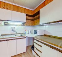 Rodinný dom Šambron, okr. Stará Ľubovňa - Kuchyňa v rodinnom dome s linkou, sporákom a podlahou s dreveným dekorom.