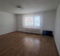 4. izb. RD Čakajovce pri Nitre  - Obývacia izba v rodinnom dome s podlahou s dreveným dekorom a oknom s bielou záclonou.