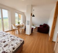 Prenájom, Apartmán v meste Krupina - Interiér 2-izbového bytu s posteľou, stolom a podlahou s dreveným dekorom.