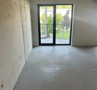 GUTHAUS - 4 izbový byt na Račianskej ulici v Bratislave - Prázdna miestnosť s veľkými oknami a betónovou podlahou v 4-izbovom byte.
