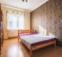 Kúpte si PÔVABNÝ 4i RD na SKVELOM POZEMKU s GARÁŽOU a HALAOU - Spálňa s drevenou posteľou a tapetou, svetlo prechádza cez záclony v rodinnom dome.