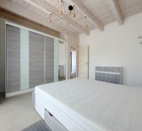 Rodinný dom s krásnym pozemkom, Jablonové - Spálňa v rodinnom dome s posteľou, šatníkom a dreveným trámovým stropom.