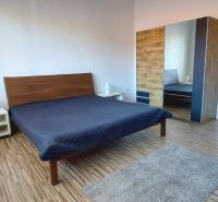 PRENÁJOM: VEĽKOMETRÁŽNY 2 IZBOVÝ BYT S 2 LOGGIAMI, CENTRUM - Spálňa v 2-izbovom byte s posteľou, skriňou a podlahou s dreveným dekorom.