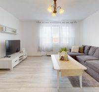  PRENÁJOM 2-izbový byt, centrum mesta s vlastným parkovaním, Topoľčany - Obývačka v 2-izbovom byte so sedačkou, TV a podlahou s dreveným dekorom.