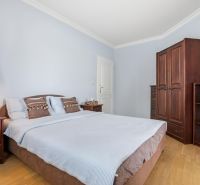 Priestranný rodinný dom s garážou | Vrakuňa, Bratislava - Spálňa v rodinnom dome s dreveným nábytkom a podlahou s dreveným dekorom.
