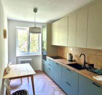 Prenájom 2 izb. bytu Račianske mýto, Bratislava - Kuchyňa v 2-izbovom byte s dreveným stolom a podlahou s dreveným dekorom.