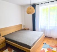 Prenájom 2 izb. bytu Račianske mýto, Bratislava - Spálňa v 2-izbovom byte s podlahou s dreveným dekorom a jednoduchým nábytkom.