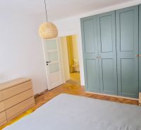 Prenájom 2 izb. bytu Račianske mýto, Bratislava - Spálňa s podlahou s dreveným dekorom, skriňou a komodou v 2-izbovom byte.