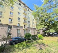 Prenájom 2 izb. bytu Račianske mýto, Bratislava - Bytový dom na Račianskej ulici v Bratislave obklopený zeleňou a zaparkovanými autami.