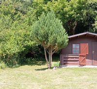 TURANY- rekreačná chata na pozemku 700m2 - Drevená chata obklopená zeleňou na ulici Černík, strom poskytuje prírodný tieň.