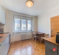 Staromestský 2i byt s balkónom na Palisádach - Kuchyňa v 2-izbovom byte s podlahou s dreveným dekorom a dreveným stolom.