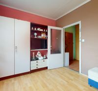 NA PREDAJ 3 IZBOVÝ BYT NA ZAČIATKU VII. SÍDLISKA, UL. PALATÍNOVA - Izba s podlahou s dreveným dekorom a jednoduchým zariadením v 3-izbovom byte.