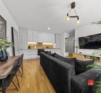 Moderný 2i apartmán v novostavbe v Starom Meste - Obývacia izba s kuchynským kútom, sedačkou, televízorom a podlahou s dreveným dekorom v 2-izbovom byte.