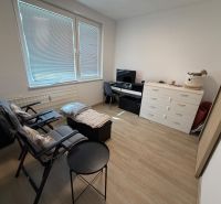 3 izbový byt s balkónom Topoľčany  - Izba v 3-izbovom byte s podlahou s dreveným dekorom, kreslami a zásuvkami.