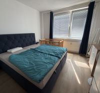 3 izbový byt s balkónom Topoľčany  - Spálňa s posteľou, detskou postieľkou a podlahou s dreveným dekorom v 3-izbovom byte.