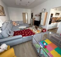 3 izbový byt s balkónom Topoľčany  - Obývacia izba v 3-izbovom byte so sivou sedačkou a detským kútikom, podlaha s dreveným dekorom.