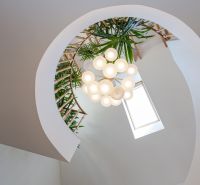 Rezidenčná vila v širšom centre Piešťan - Špirálové schodisko s rastlinami, svietidlom a strešným oknom v rodinnom dome.