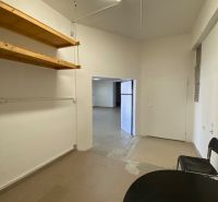 Prenájom 148,25 m² showroom, predajňa | Zlatovce - Obchodné priestory s policami, stolom a stoličkami, biele steny a jednoduché osvetlenie.