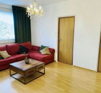 Prenajom 2,5-izbový byt v Karlovej Vsi – 48 m², výhľad do Líščieho - Obývačka v 2-izbovom byte s červenou sedačkou, luster a podlaha s dreveným dekorom.