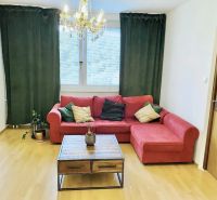 Prenajom 2,5-izbový byt v Karlovej Vsi – 48 m², výhľad do Líščieho - Obývacia izba v 2-izbovom byte s červenou pohovkou, stolíkom a závesmi.