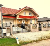 6 - izbový rodinný dom v obci Ratkovce, novostavba - Rodinný dom v Ratkovciach s červenou strechou, plotom a spevneným dvorom z kamienkov.