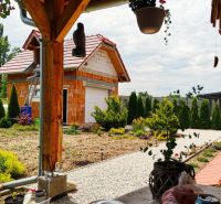 6 - izbový rodinný dom v obci Ratkovce, novostavba - Upravená záhrada a garáž pri rodinnom dome v Ratkovciach, obklopené zeleňou a drevom.