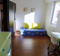 PRENÁJOM: SLNEČNÝ 3 IZBOVÝ BYT S BALKÓNOM A PARKOVANÍM, CENTRUM - Izba s podlahou s dreveným dekorom, pohovkou, stolom a sviežimi farbami v 3-izbovom byte.