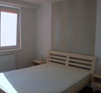 PRENÁJOM: SLNEČNÝ 3 IZBOVÝ BYT S BALKÓNOM A PARKOVANÍM, CENTRUM - Spálňa v 3-izbovom byte s posteľou, svetlými stenami a podlahou s dreveným dekorom.