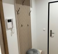 Kompletne zariadený 3-izbový byt s balkónom | PRÚDY Trnava - Chodba s vešiakom a podlahou s dreveným dekorom v 3-izbovom byte.